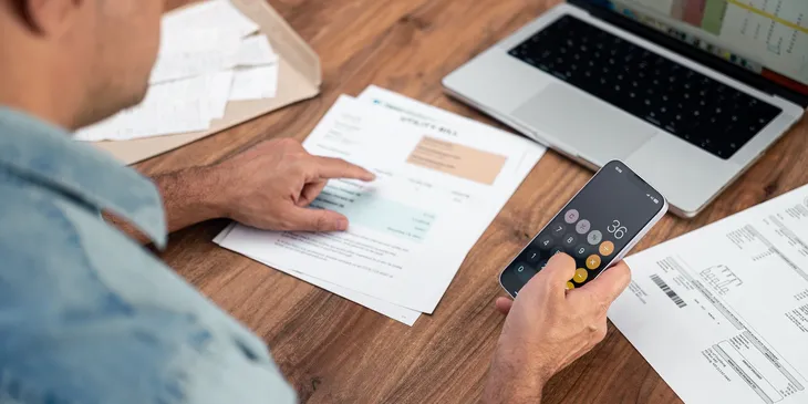 Individual managing finances with laptop and phone